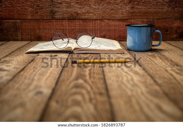 Vintage expedition journal on a rustic\
picnic table  with a cup of tea - handwriting and drawing in travel\
log  (property release attached), selective\
focus.