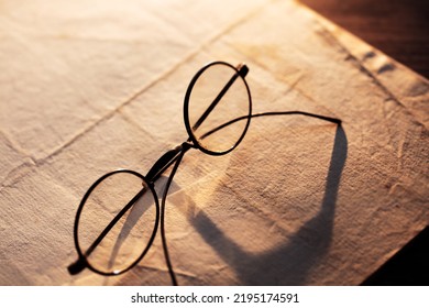 Vintage eyeglasses on an old paper.  Low key incandescent lighting. Shallow depth of field. - Shutterstock ID 2195174591