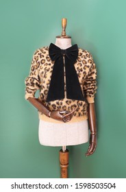 Vintage Fashion Tailor Dummy With A Big Black Velvet Bow And Leopard Pattern Pullover On Green Background