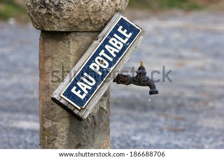 Vintage faucet of drinking water from which the water drips, signed in French,  outside by the street