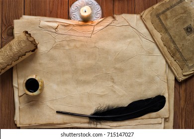 vintage feather with paper and ink on table in light of candle