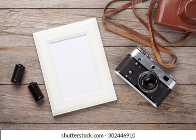 Vintage Film Camera And Blank Photo Frame On Wooden Table. Top View