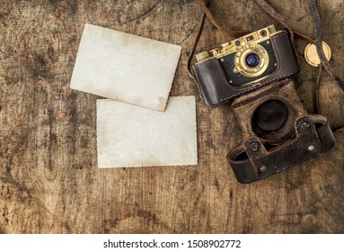 Vintage Film Camera And Old Photos On Wooden Background. Nostalgic Still Life