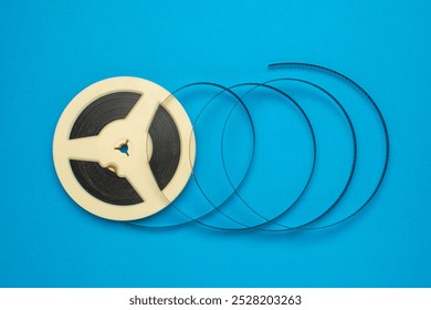 Vintage Film Reel Unwinding on Vibrant Blue Background - Retro Cinema, Analog Media Concept - Powered by Shutterstock