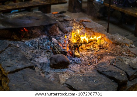 Vintage fireplace for cooking food inside the old wooden viking longhouse in the reconstruction of ancient village. Interior of viking house.