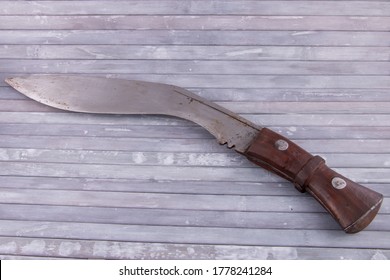 Vintage Ghurkha Kukri Knife, slightly rusty on curved metal blade. Isolated on gray wooden background