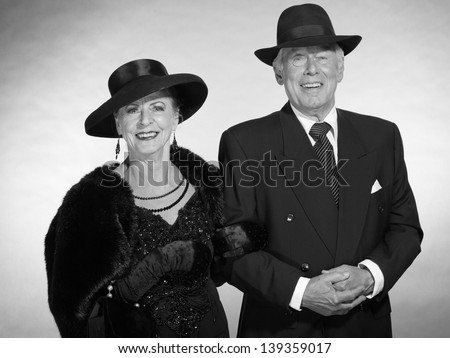 Vintage glamour senior couple wearing black hat. Black and white photo.