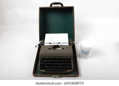 Vintage gray typewriter and Debugger Blanco bottle showing computer code. Conceptual link between analog writing and coding.
