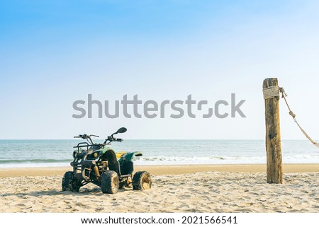 Vintage green ATV on the sandy beach. Quad ATV all terrain vehicle parked on beach, Motor bikes ready for action with summer sun flaring on bright day. Outdoor extreme activity adrenaline sport.