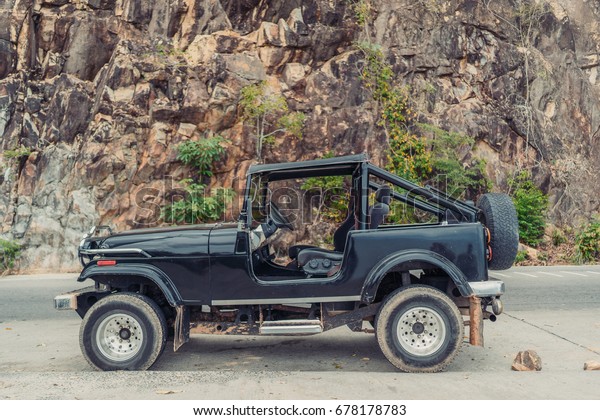 Vintage handmade 4x4 off road\
truck vehicle at the beautiful mountain road. Offroad adventure\
tour vacation concept. Side view. Car expedition wallpaper. Shallow\
focus.