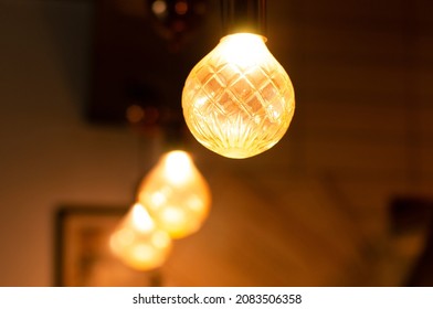 Vintage hanging Edison light bulbs over dark background. Light bulbs in cafe, restaurant or room with dim light. Stylish, elegant and decorative lighting with abstract background. - Powered by Shutterstock