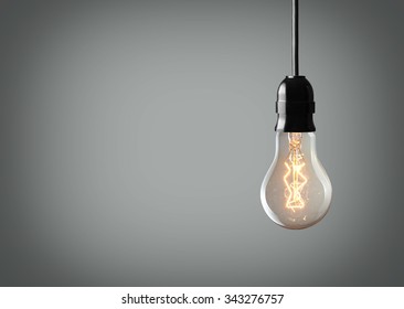 Vintage hanging light bulb over gray background 