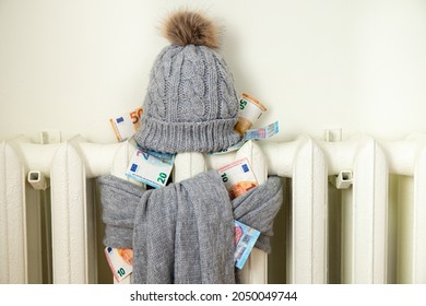 Vintage Heating Radiator With Winter Hat And Scarf Stuffed With Euro Money. The Electricity Bill Goes Up, European Energy Crisis Concept. 