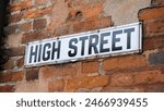 Vintage high street sign on old, rustic, worn and crumbling red brick wall in urban town city