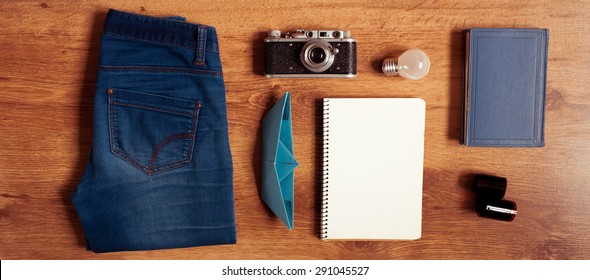 Vintage Hipster Packing: Clothes, Old Camera, Notebook,book,origami Boat On Wooden Floor. Top View. 