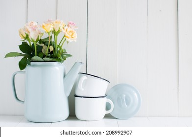 Vintage home arrangement, summer flowers and enamelware on a barn wall background, soft pastel colors.