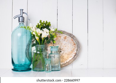 Vintage Home Decor, Ancient Turquoise Siphon, Freesias Bouquet And Bottles On A White Wooden Background.