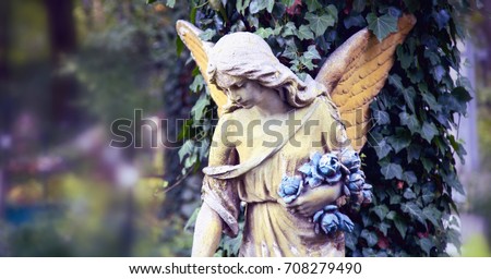 Vintage image of a sad angel against the background of leaves (fragment)