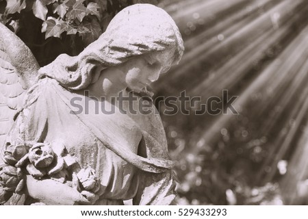 Vintage image of a sad angel on a cemetery against the background of leaves