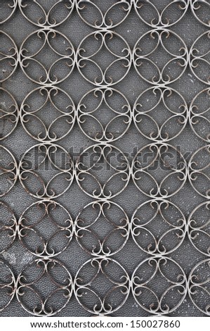 Vintage iron door frame with circles pattern detail and stained glass background.
