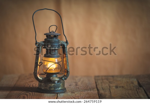 vintage\
kerosene oil lantern lamp burning with a soft glow light in an\
antique rustic country barn with aged wood\
floor