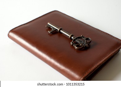 A Vintage Key Is Over A Brown Leather Passport Holder