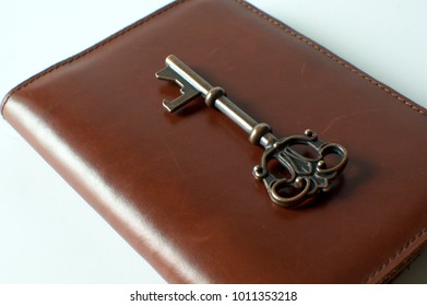 A Vintage Key Is Over A Brown Leather Passport Holder