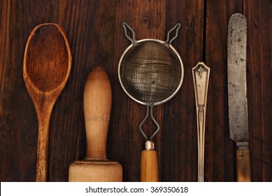 Vintage kitchen utensils on rustic wood background.  Closeup with low key, natural side-lighting for effect.