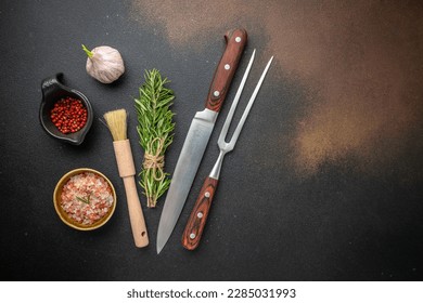 vintage kitchenware kitchen utensils: Meat Fork and Butcher Cleaver and herbs knife, ingredients for grilling meat steak on a dark background. place for text, top view,
