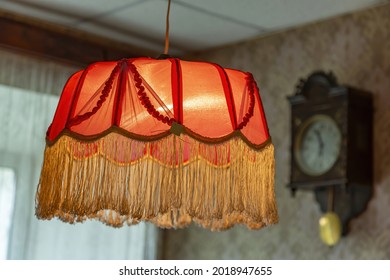 Vintage lampshade made of red fabric with fringes as an element of the decor of the interior of the room