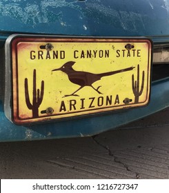 Vintage License Plate That Reads:  Grand Canyon State, Arizona With Images Of Cactus And Roadrunner On Blue Car