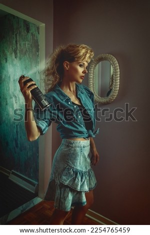 vintage lifestyle portrait of a young blonde woman in a late 80s, early 90s, interior decor, wearing a denim outfit and styling her teased hair and bangs with hairspray