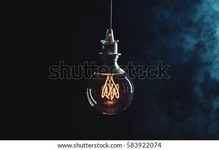 Vintage lightbulb on dark background with bright yellow shining wire