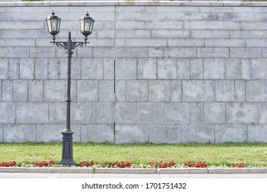 vintage lightpost near the grey wall and green grass in Yekaterinburg city