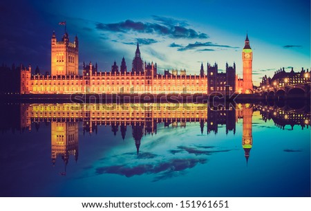 Vintage looking Big Ben and Houses of Parliament (Westminster Palace) in London reflected in River Thames at night