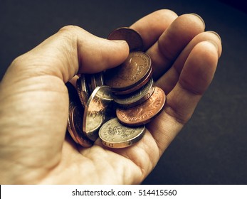 Vintage looking Hand with British Pounds coins (UK currency) over a dark background