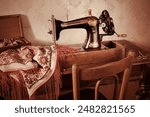 A vintage manual sewing machine on an old wooden table; fabric, scissors, box with spools of thread, back of a Viennese wooden chair