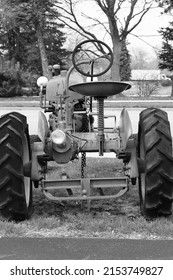 Vintage mechanical combustion engine farm tractor in black and white.
