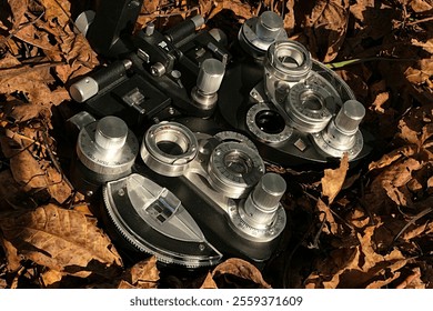 Vintage mechanical manual phoropter for diagnostic of eye refraction lying in brown autumn leaves, sunlit by afternoon sunshine. - Powered by Shutterstock