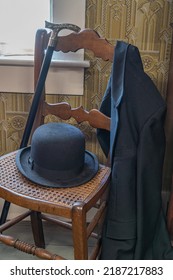 Sombrero vintage de los hombres de bolos, bastón y chaqueta en una silla de atrás de bastón de madera.