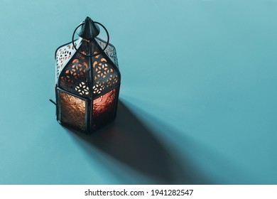 Vintage Metal Arab Lantern With Colorful Glass Decor With Long Shadow. Blue Turquoise Table Background. Holy Month Ramadan Greeting Card, Invitation. Islam Web Banner. Top View, No People. Eid Ul Fitr