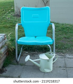 Vintage Metal Lawn Chair Circa 50's With Old Metal Watering Can Waiting Patiently In The Garden For Spring