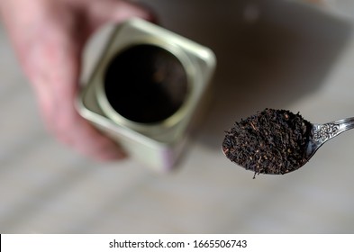 Vintage Metal Spoon Of Dry Tea Leaves. A Can For Storing Tea Leaves In The Background. Making A Traditional Hot Drink. View From Above. Selective Focus.