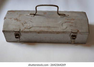 Vintage metal toolbox with rusty patina and embossed wrench design. Ideal for themes of repair, DIY, mechanics, handyman work, retro tools, and industrial style.