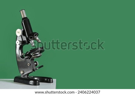 Vintage microscope on table near green wall