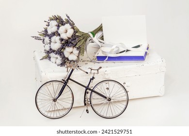 Vintage miniature bike next to suitcase and bouquet of dried flowers, book and  open greeting card. Romantic gift concept - Powered by Shutterstock