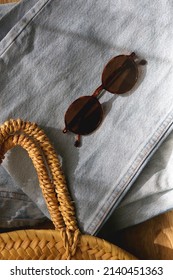 Vintage Mom Jeans, Round Straw Bag And Sunglasses On Wooden Background. Flat Lay.