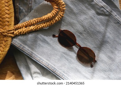 Vintage Mom Jeans, Round Straw Bag And Sunglasses On Wooden Background. Flat Lay.