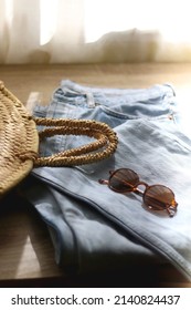 Vintage Mom Jeans, Round Straw Bag And Sunglasses On Wooden Background. Selective Focus.