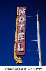 A vintage motel sign with an arrow in frount of blue sku